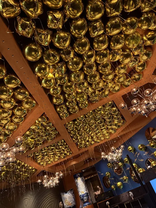 Hundreds of gold balloons filling a carved wood ceiling at a venue