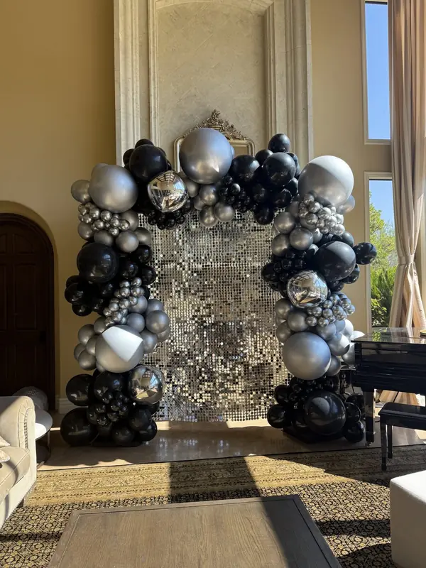 Silver shimmer wall framed by a black and silver balloon arch
