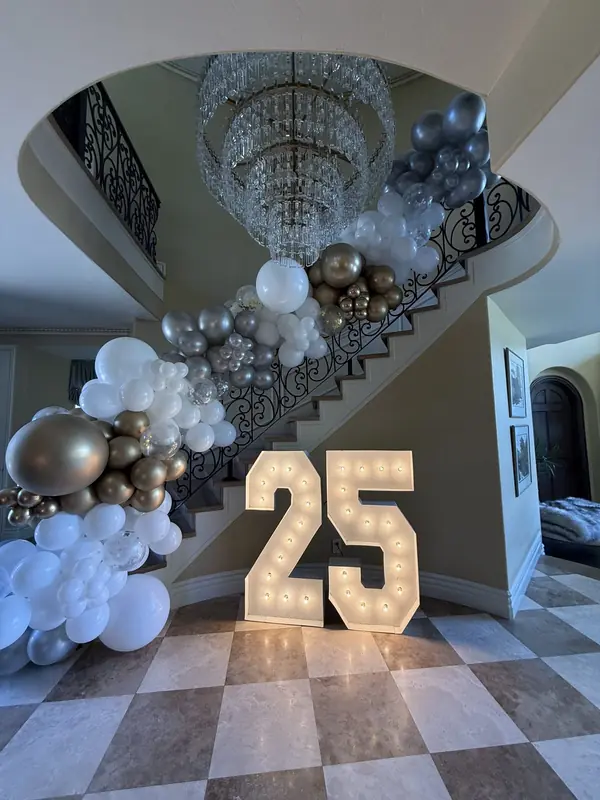 White, silver and gold balloon garland cascading down a grand staircase